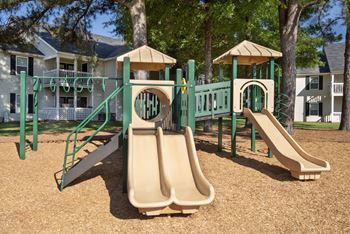 a playground with slides and swings in front of a house
